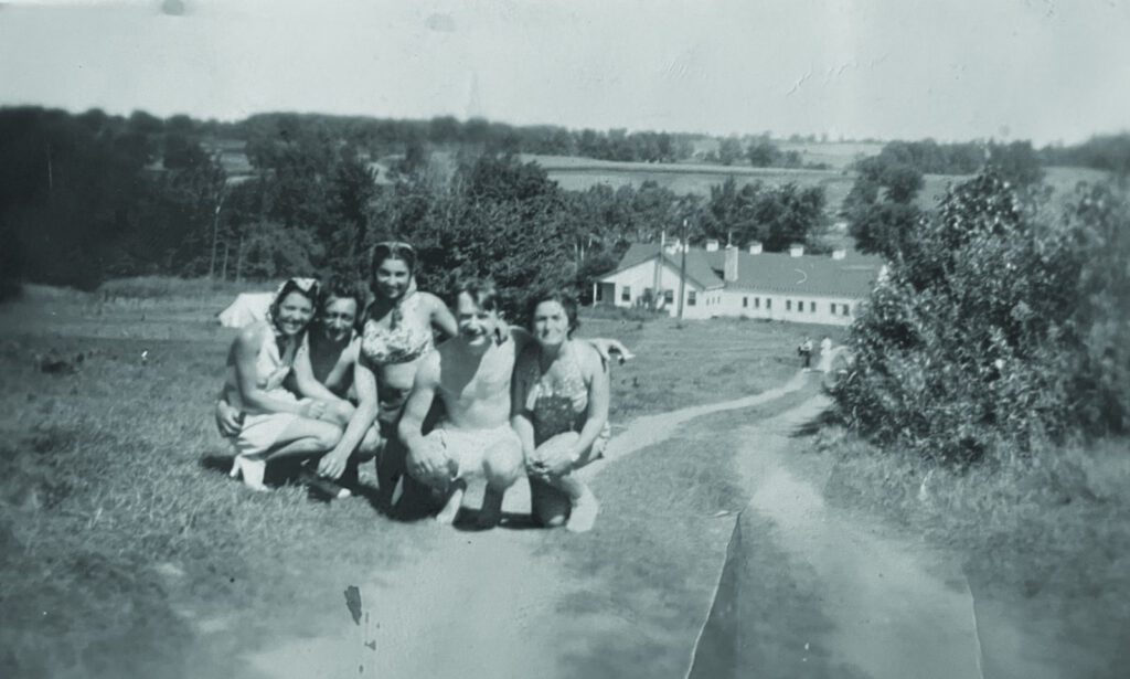 Young women pose on the hillside above the original Dining Hall