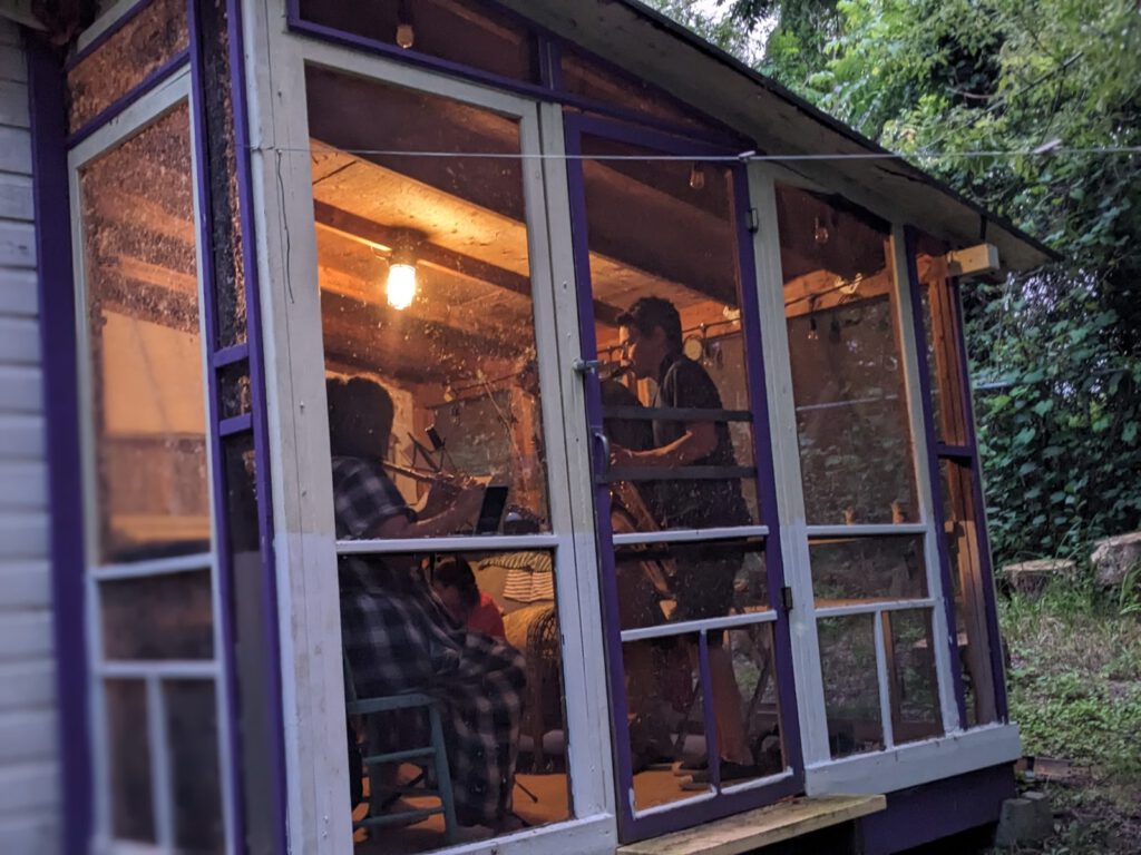 Musicians jam in a screened cabin at dusk