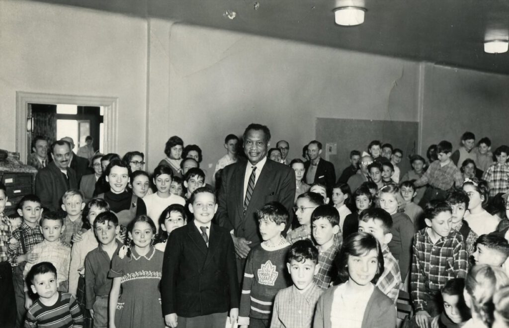 American movie star and singer Paul Robeson, a long-time friend of UJPO, dropped in to meet MWS children at UJPO’s home, 83 Christie Street, in 1956 on his way to sing for a union convention in Sudbury
